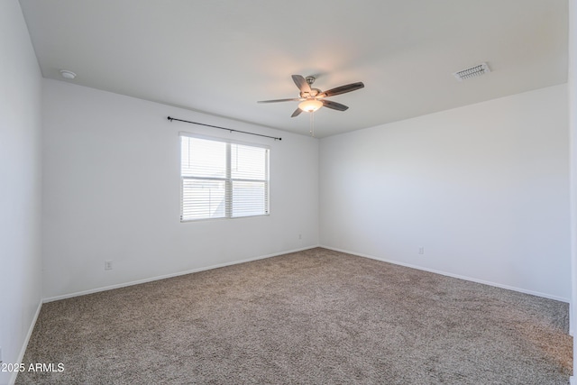 empty room with ceiling fan, carpet floors, visible vents, and baseboards