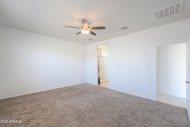 empty room with light carpet, light tile patterned floors, ceiling fan, and visible vents