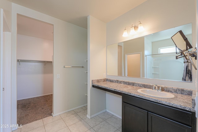 bathroom featuring tile patterned floors, a spacious closet, baseboards, and vanity