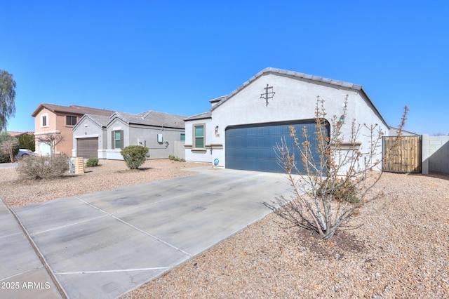 view of front of house with driveway, a garage, fence, and stucco siding