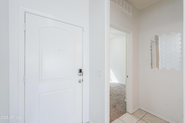 interior space with light tile patterned floors, baseboards, visible vents, and light colored carpet