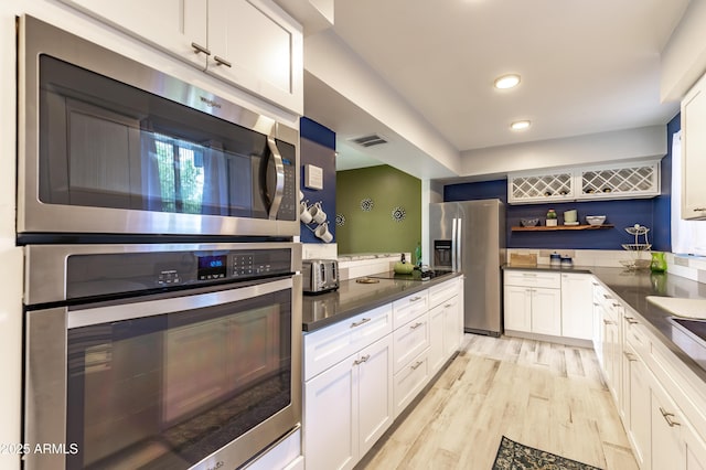 kitchen with white cabinets, light wood-type flooring, and appliances with stainless steel finishes