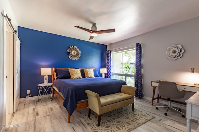 bedroom with ceiling fan, a barn door, and hardwood / wood-style floors