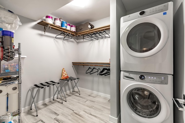 laundry room featuring light hardwood / wood-style floors and stacked washer / dryer