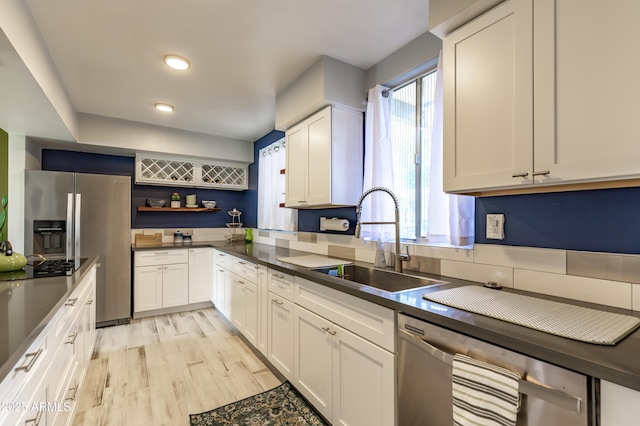 kitchen with sink, white cabinetry, appliances with stainless steel finishes, and light hardwood / wood-style flooring