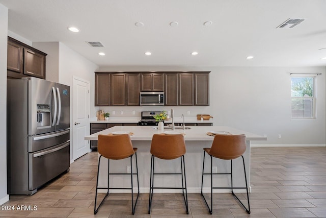 kitchen with stainless steel appliances, a sink, visible vents, and dark brown cabinetry