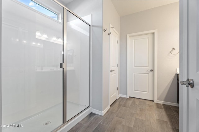 bathroom with hardwood / wood-style floors and a shower with shower door