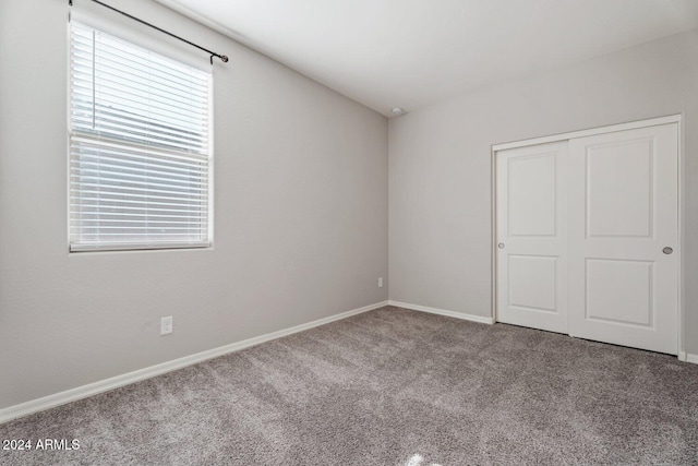 unfurnished bedroom with carpet floors, a closet, and baseboards