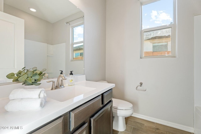 bathroom with a shower, vanity, wood-type flooring, and toilet