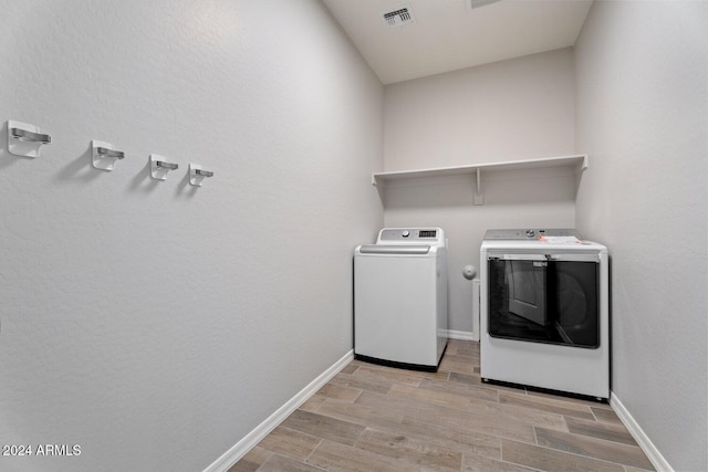 clothes washing area with independent washer and dryer and light wood-type flooring