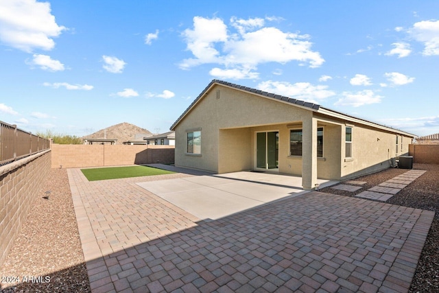 rear view of property featuring a patio, cooling unit, a fenced backyard, and stucco siding