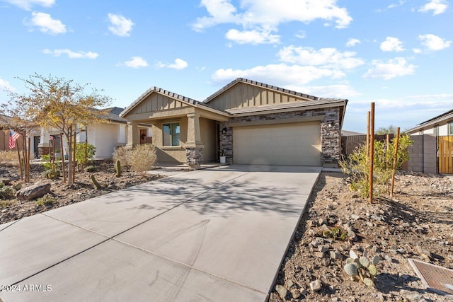 view of front of home featuring a garage, concrete driveway, stone siding, fence, and board and batten siding