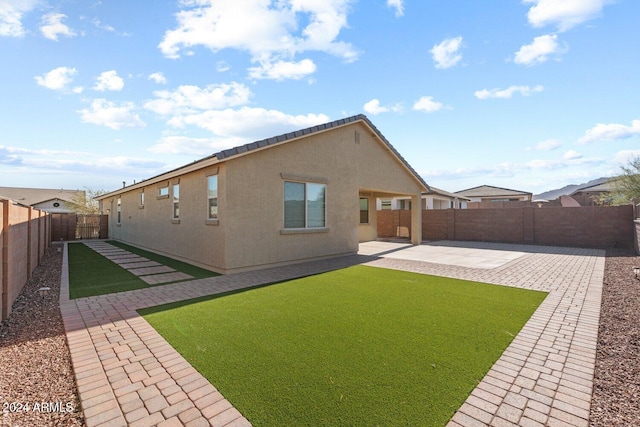 back of house featuring a patio, a yard, a fenced backyard, and stucco siding