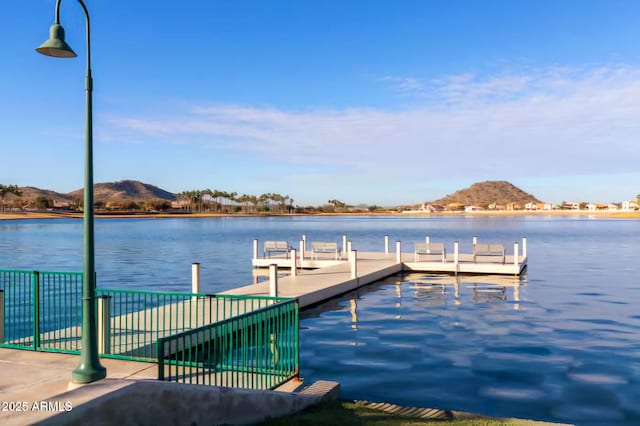 view of dock with a water view and fence