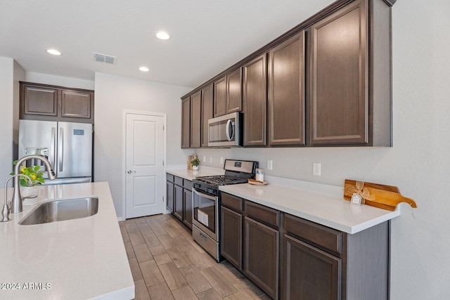 kitchen featuring visible vents, appliances with stainless steel finishes, light countertops, dark brown cabinets, and a sink