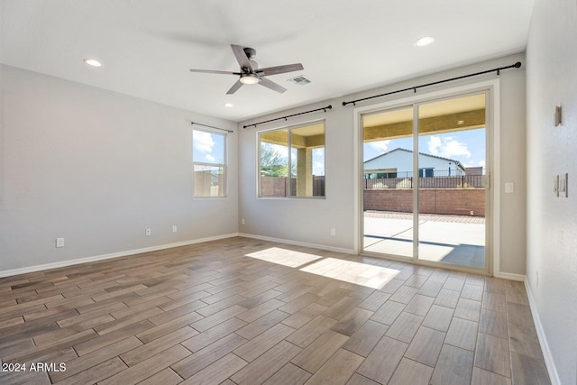 empty room featuring ceiling fan, a healthy amount of sunlight, and light hardwood / wood-style flooring