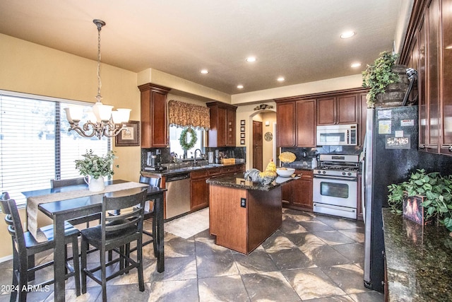 kitchen featuring hanging light fixtures, decorative backsplash, a kitchen island, stainless steel appliances, and a chandelier