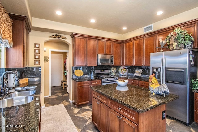 kitchen with backsplash, a kitchen island, sink, and appliances with stainless steel finishes