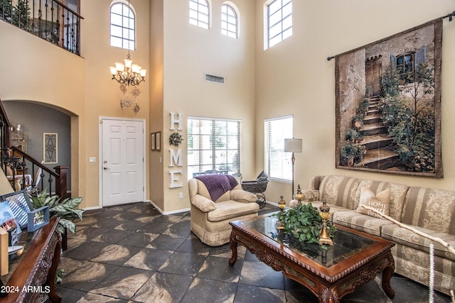 living room featuring a high ceiling, plenty of natural light, and a notable chandelier