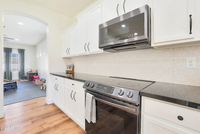 kitchen with backsplash, appliances with stainless steel finishes, light wood-type flooring, and white cabinets