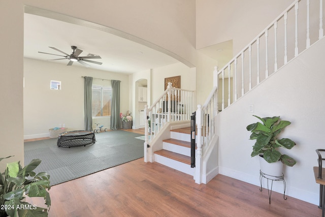 staircase with wood-type flooring and ceiling fan