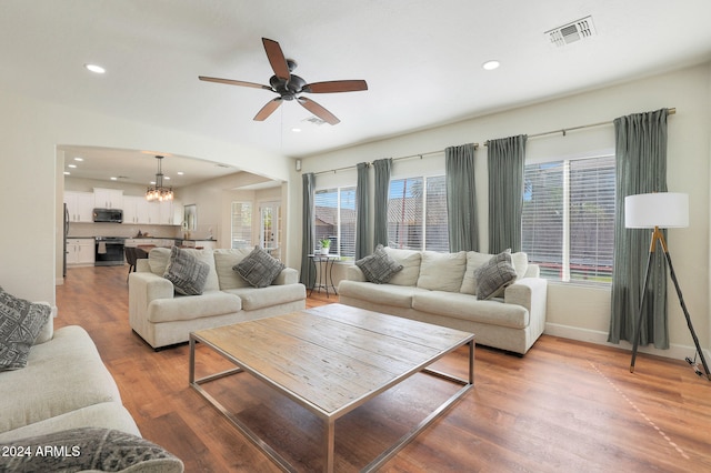 living room with hardwood / wood-style flooring and ceiling fan with notable chandelier