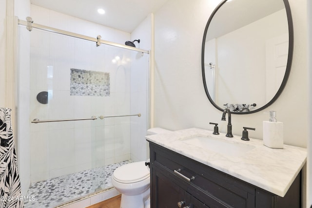 bathroom with toilet, a shower with shower door, and vanity