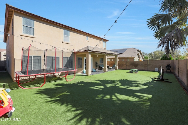 back of property featuring central AC, a trampoline, a patio, and a lawn