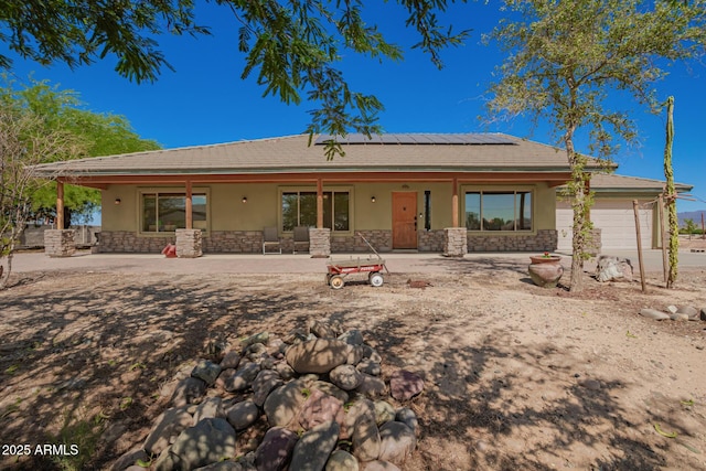 4621 S 179th Dr, Goodyear, AZ 85338 - view of front facade with stone siding, stucco siding, covered porch, roof mounted solar panels, and an attached garage