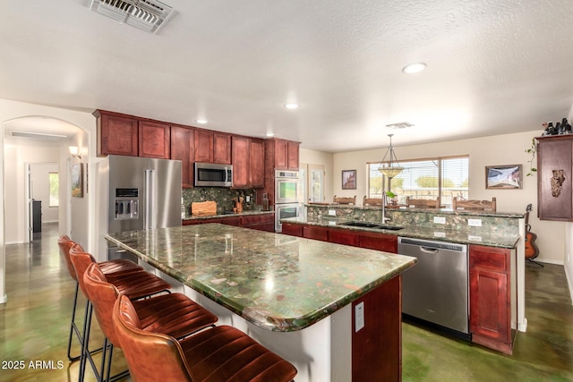 4621 S 179th Dr, Goodyear, AZ 85338 - kitchen with stainless steel appliances, a kitchen island with sink, concrete floors, dark brown cabinets, and recessed lighting