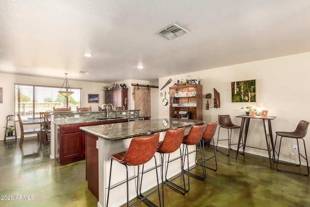 4621 S 179th Dr, Goodyear, AZ 85338 - kitchen with finished concrete floors, a barn door, a kitchen breakfast bar, a peninsula, and recessed lighting