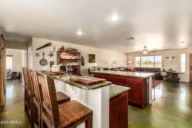 4621 S 179th Dr, Goodyear, AZ 85338 - kitchen featuring concrete floors, a center island, open floor plan, a ceiling fan, and a breakfast bar area
