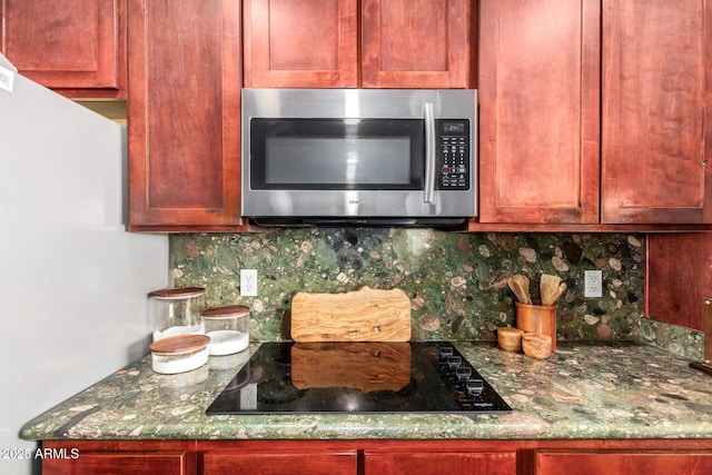 4621 S 179th Dr, Goodyear, AZ 85338 - kitchen view of stainless steel microwave, decorative backsplash, black electric stovetop, dark brown cabinets, and freestanding refrigerator