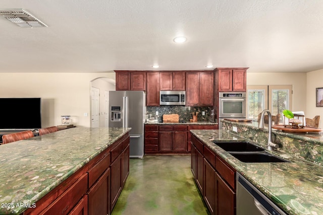 4621 S 179th Dr, Goodyear, AZ 85338 - kitchen featuring stainless steel appliances, backsplash, dark stone countertops, concrete flooring, and recessed lighting