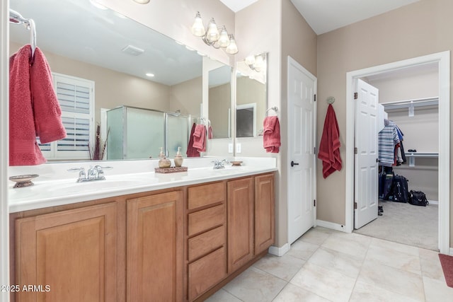 bathroom featuring a spacious closet, double vanity, a stall shower, tile patterned floors, and a sink