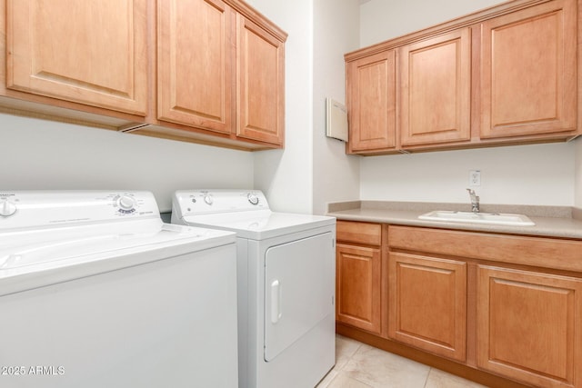 laundry area featuring washing machine and dryer, light tile patterned floors, cabinet space, and a sink