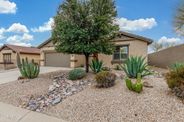 view of front of property with concrete driveway, fence, a garage, and stucco siding