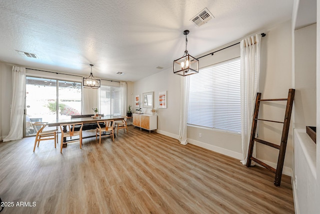 dining area with a notable chandelier, light hardwood / wood-style flooring, and a textured ceiling