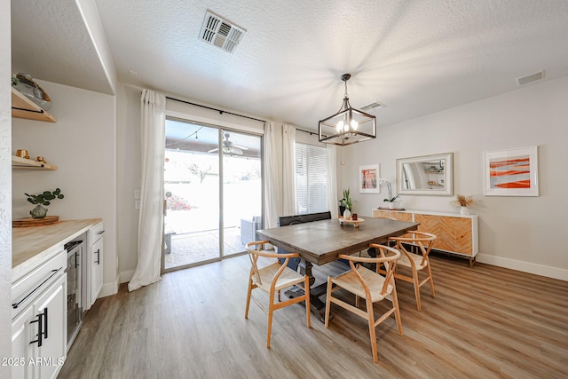 dining area with light hardwood / wood-style flooring, a chandelier, and a textured ceiling