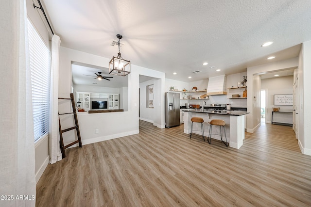 kitchen featuring stainless steel refrigerator with ice dispenser, decorative light fixtures, a breakfast bar area, and light hardwood / wood-style flooring