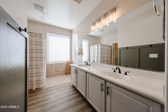 bathroom with vanity, wood-type flooring, a textured ceiling, and walk in shower