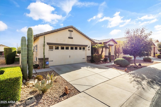 view of front of property featuring an attached garage, a tile roof, driveway, stone siding, and stucco siding