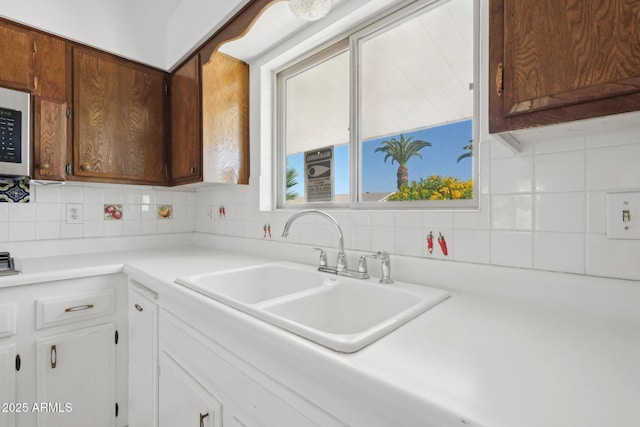 11044 W Cheryl Dr, Sun City, AZ 85351 - kitchen featuring a sink, tasteful backsplash, light countertops, and white cabinetry