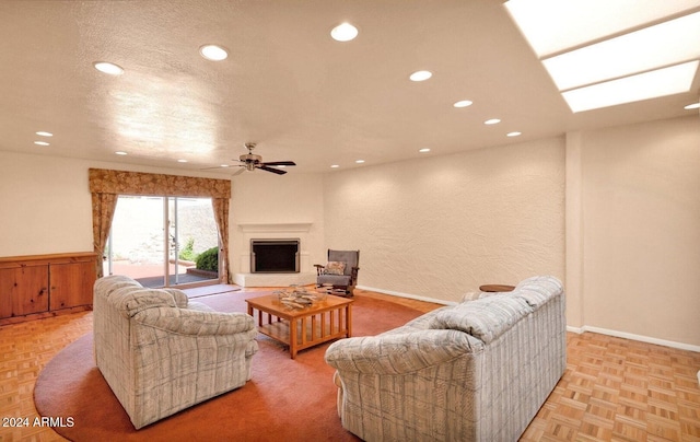 living room featuring ceiling fan, light parquet flooring, and a textured ceiling