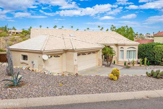 view of front of home featuring stucco siding, a tiled roof, an attached garage, and driveway