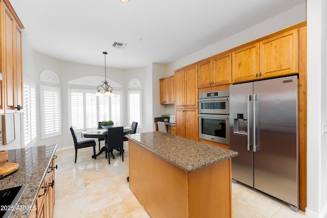 kitchen with stainless steel appliances, light stone countertops, visible vents, and brown cabinets