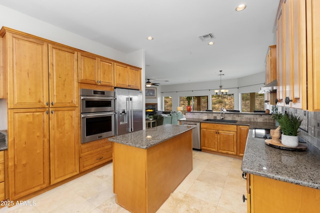 kitchen with visible vents, a sink, stainless steel appliances, under cabinet range hood, and ceiling fan with notable chandelier