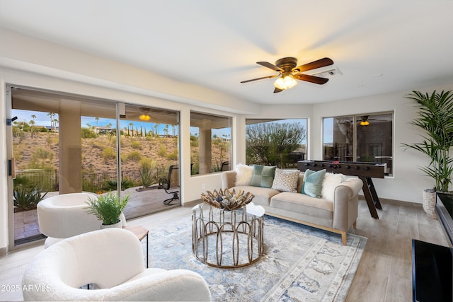 living area with visible vents, light wood-style flooring, baseboards, and a ceiling fan