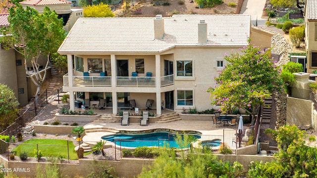 back of property featuring a tile roof, a balcony, and a patio area