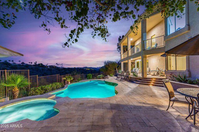 pool at dusk with a fenced backyard, a fenced in pool, an in ground hot tub, and a patio